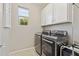 A well-lit laundry room with modern appliances, white cabinets, and tile flooring at 1941 W Yellowstone Way, Chandler, AZ 85248