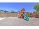 Backyard view of playground with slide, swing, climbing ladder, and lookout, all sitting on a gravel surface at 2041 E Des Moines St, Mesa, AZ 85213