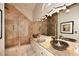 Bright bathroom featuring dual sinks, granite counters, neutral cabinetry, and a walk-in shower with tile surround at 21609 N 61St Ave, Glendale, AZ 85308