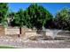 An attractive community entrance sign surrounded by plants and rocks, featuring a water feature and lush green trees at 21609 N 61St Ave, Glendale, AZ 85308