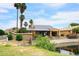 The rear exterior features solar panels, a covered patio with patio furniture, lovely landscaping, and backyard views of the lake at 21609 N 61St Ave, Glendale, AZ 85308
