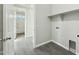 Bright laundry room featuring wood-look tile floor, gray walls, shelf, and utility hook-ups at 22351 S Manzanilla Rd, Buckeye, AZ 85326