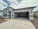 The house features a spacious driveway leading to an open two-car garage, complemented by desert landscaping at 25183 N 183Rd Dr, Wittmann, AZ 85361