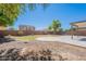Wide shot of the backyard featuring rock landscaping, patio, block wall, and shade from a tree at 2847 S 161St Dr, Goodyear, AZ 85338