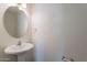 Powder room featuring a white pedestal sink and round mirror at 2847 S 161St Dr, Goodyear, AZ 85338