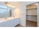 Bathroom featuring dual sinks, a large mirror, and walk-in closet with shelving at 2847 S 161St Dr, Goodyear, AZ 85338