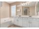 Bright bathroom featuring a soaking tub and a dual sink vanity with white cabinets and a large mirror at 4426 E Coyote Wash Dr, Cave Creek, AZ 85331