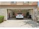 Garage with garage door open featuring cabinets, shelving, water heater, ladder, and white car parked inside at 4734 W Golden Ln, Glendale, AZ 85302