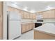 Kitchen with white appliances, wood cabinets, and tile flooring at 4734 W Golden Ln, Glendale, AZ 85302