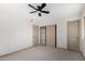 Bedroom with neutral walls, carpet flooring, ceiling fan, closet and two doors at 48451 N 27Th Ave, New River, AZ 85087