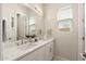 Bright bathroom boasts dual sinks, white cabinetry, quartz countertops, and a large mirror at 5954 E Cat Balue Dr, Phoenix, AZ 85054