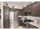 Close up of the kitchen featuring stainless-steel appliances, dark cabinets, and light granite countertops at 6937 E Purple Shade Cir, Scottsdale, AZ 85266