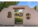 Enchanting backyard view through a decorative wall, showcasing a pool, tiki hut, and lush greenery at 7315 W Monte Lindo Ln, Glendale, AZ 85310