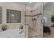 A tiled bathroom featuring a shower, a soaking tub under a glass block window, and vanity with tiled backsplash at 7315 W Monte Lindo Ln, Glendale, AZ 85310