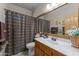 Bathroom with wooden vanity, framed mirror and shower with decorative curtain at 7315 W Monte Lindo Ln, Glendale, AZ 85310