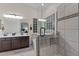 Bright bathroom featuring double vanity, glass block window, and glass-enclosed shower with tile surround at 7315 W Monte Lindo Ln, Glendale, AZ 85310