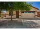 Charming single-story home featuring a two-car garage, desert landscaping, and mature shade tree at 7324 S 254Th Dr, Buckeye, AZ 85326