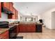 A functional kitchen featuring rich wood cabinets, granite countertops, and black appliances at 7324 S 254Th Dr, Buckeye, AZ 85326