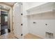 Functional laundry room with ample shelving and hook storage, adjacent to the garage entry at 9921 E Acceleration Dr, Mesa, AZ 85212