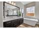 Bright bathroom featuring dual vanities and sinks, a soaking tub, and warm wood floors at 1145 E Gleneagle Dr, Chandler, AZ 85249
