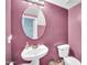 Unique bathroom with a pedestal sink, round mirror, and vibrant plum colored walls at 12022 W Belmont W Dr, Avondale, AZ 85323