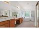 Bright bathroom featuring dual sinks, a soaking tub with glass block window, and a shower with a glass door at 1420 W Raven Dr, Chandler, AZ 85286