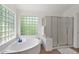 A soaking tub sits in front of a glass block window, and a shower has a glass door in this bright bathroom at 1420 W Raven Dr, Chandler, AZ 85286