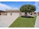 Home featuring a spacious driveway leading to a 2-car garage with a manicured lawn and mature shade tree at 1670 E Whitten St, Chandler, AZ 85225