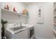 Functional laundry room equipped with modern washer and dryer units, built-in shelving, and ample storage solutions at 17219 W La Luz Rd, Surprise, AZ 85387