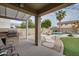Backyard with built in grill, seating area, mature landscaping and a sparkling pool with waterfall feature at 17562 W Agave Ct, Goodyear, AZ 85338