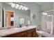 Bathroom featuring double sinks, granite counters, framed mirror, and glass enclosed shower at 17562 W Agave Ct, Goodyear, AZ 85338