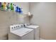 Functional laundry room featuring white washer and dryer with shelving above for storage at 17562 W Agave Ct, Goodyear, AZ 85338