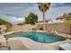 Backyard swimming pool with natural rock waterfall feature and mature palm tree at 17562 W Agave Ct, Goodyear, AZ 85338