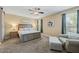 Bright main bedroom boasts a king bed, ceiling fan and sitting chair at 18309 N Crestview Ln, Maricopa, AZ 85138