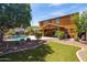 Expansive backyard featuring a sparkling pool, covered patio, and lush green lawn for outdoor enjoyment at 18649 W Williams St, Goodyear, AZ 85338