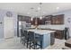Contemporary kitchen with dark cabinets, a stainless steel refrigerator, and a center island with seating at 18649 W Williams St, Goodyear, AZ 85338