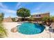 Beautiful backyard pool with stone features, lush greenery, and a charming waterfall feature at 18649 W Williams St, Goodyear, AZ 85338