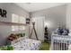 Playful bedroom with a bed, a crib, shelving with toys and a large window bringing in natural light at 19342 W Morning Glory Dr, Buckeye, AZ 85326