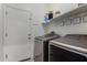 Functional laundry room with modern washer and dryer, a shelf for storage, and a door to another room at 19342 W Morning Glory Dr, Buckeye, AZ 85326