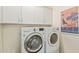 Well-organized laundry room with white cabinets, front-load washer/dryer, and charming decor at 1951 W Plum Rd, Phoenix, AZ 85085