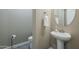 Stylish powder room with pedestal sink, round mirror, and neutral color palette at 22255 E Quintero Rd, Queen Creek, AZ 85142