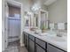 Bathroom featuring a double vanity with granite counters, decorative mirrors, and a shower-tub combo for convenience at 22255 E Quintero Rd, Queen Creek, AZ 85142