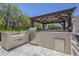 Outdoor kitchen featuring a built-in BBQ, stainless steel storage, and a covered dining area on a stone tile patio at 22255 E Quintero Rd, Queen Creek, AZ 85142