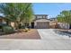 Two-story home featuring a two-car garage, desert landscaping, and mature shade trees at 22341 N 100Th Ln, Peoria, AZ 85383