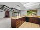 View of kitchen and living room with wood cabinets, light countertops, and brick fireplace at 2264 S Don Carlos --, Mesa, AZ 85202