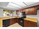 Well-lit kitchen with wood cabinets, garden window, and black appliances at 2264 S Don Carlos --, Mesa, AZ 85202