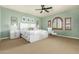 Serene main bedroom featuring plush carpet, decorative windows, a ceiling fan, and a cozy seating area at 3554 N Hooper St, Buckeye, AZ 85396