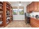 Office with a wall of dark wood bookshelves, built-in cabinets, and two windows for ample natural light at 3554 N Hooper St, Buckeye, AZ 85396