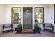 Welcoming front porch with comfortable chairs, potted plants, and a wreath on the dark-stained front door at 3684 E Boot Track Trl, Gilbert, AZ 85296
