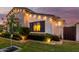 Charming home exterior featuring elegant lighting, lush landscaping, and a welcoming gate at twilight at 3684 E Boot Track Trl, Gilbert, AZ 85296